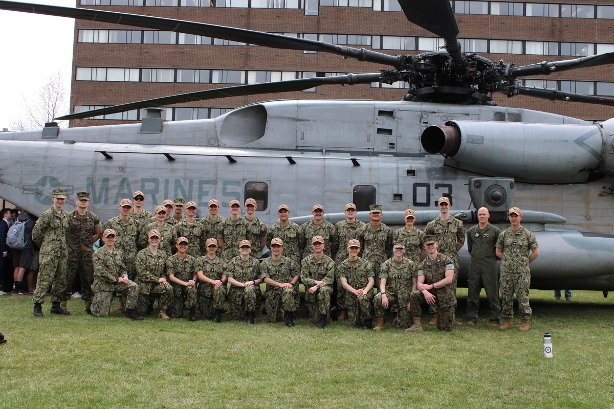 a group of people in uniform posing for a photo in front of a helicopter